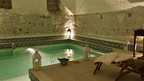 An indoor swimming pool with a tiled floor, a bench, and a lantern.
