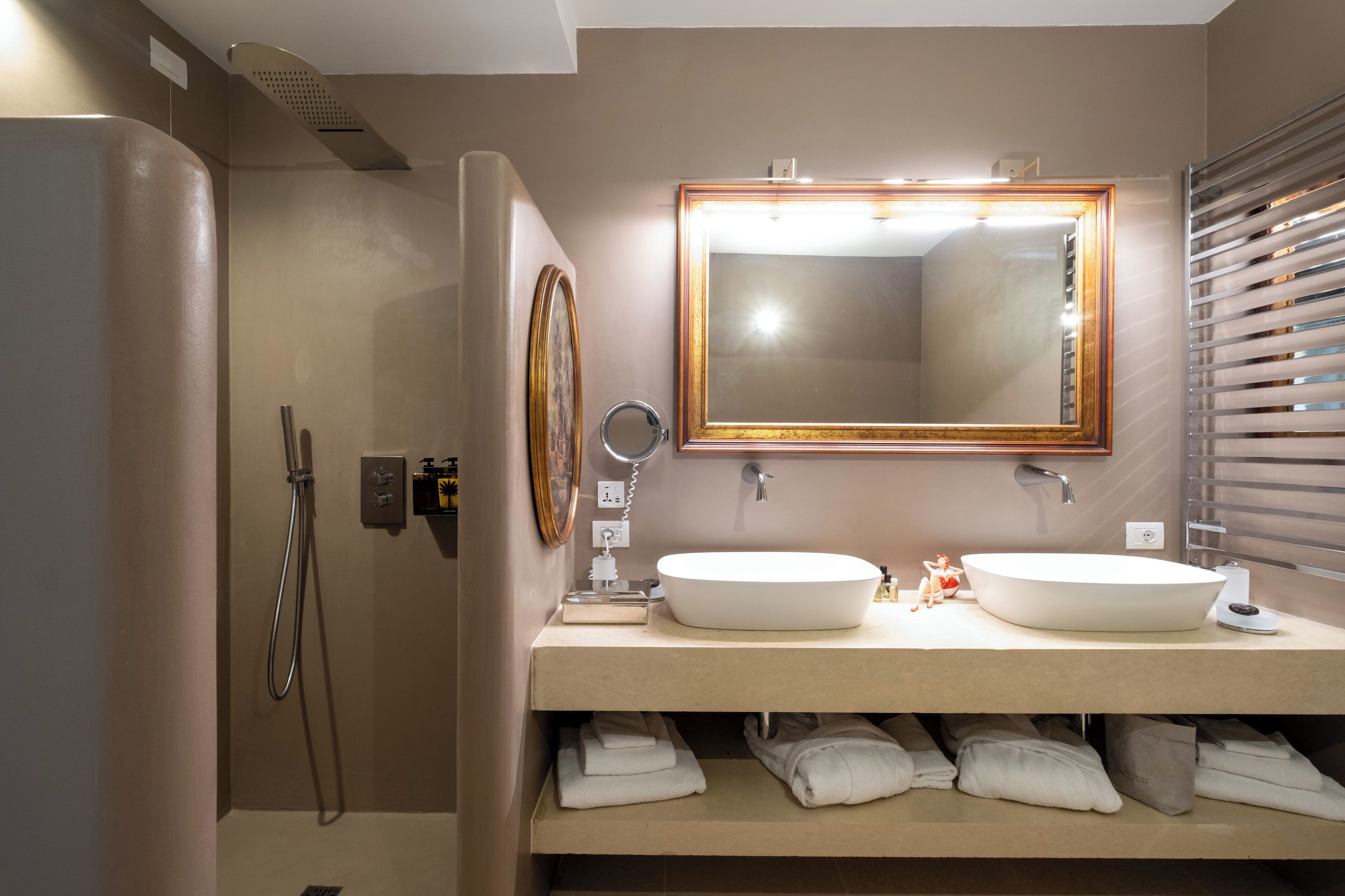 Un baño con lavamanos doble, un espejo grande, ducha y toallero.
