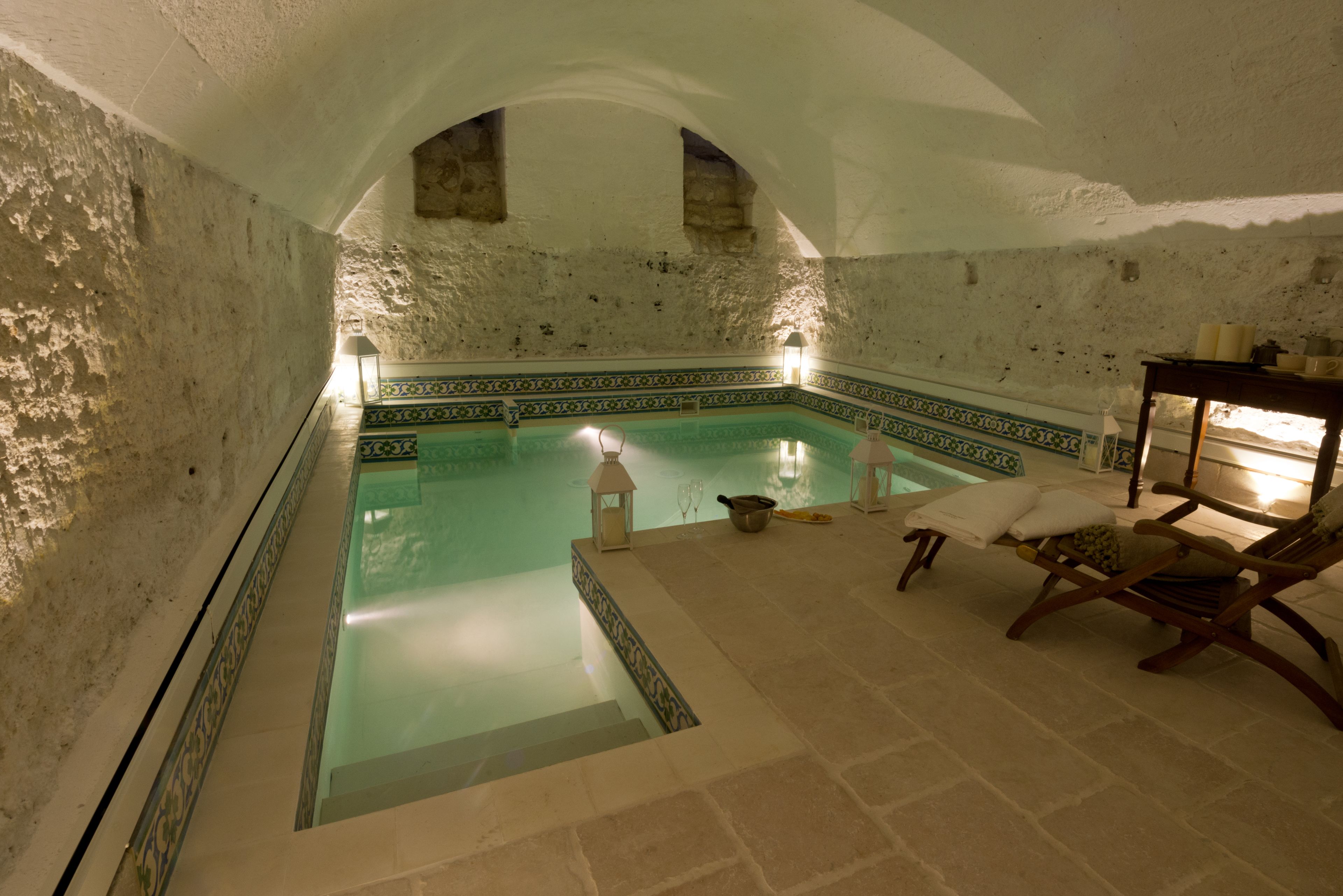 Un área de spa con piscina, paredes de piedra y una silla de madera.
