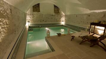 Un área de spa con piscina, paredes de piedra y una silla de madera.