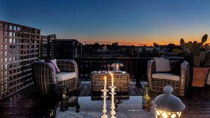 A rooftop terrace with wicker furniture, a table with candles, and a lantern.
