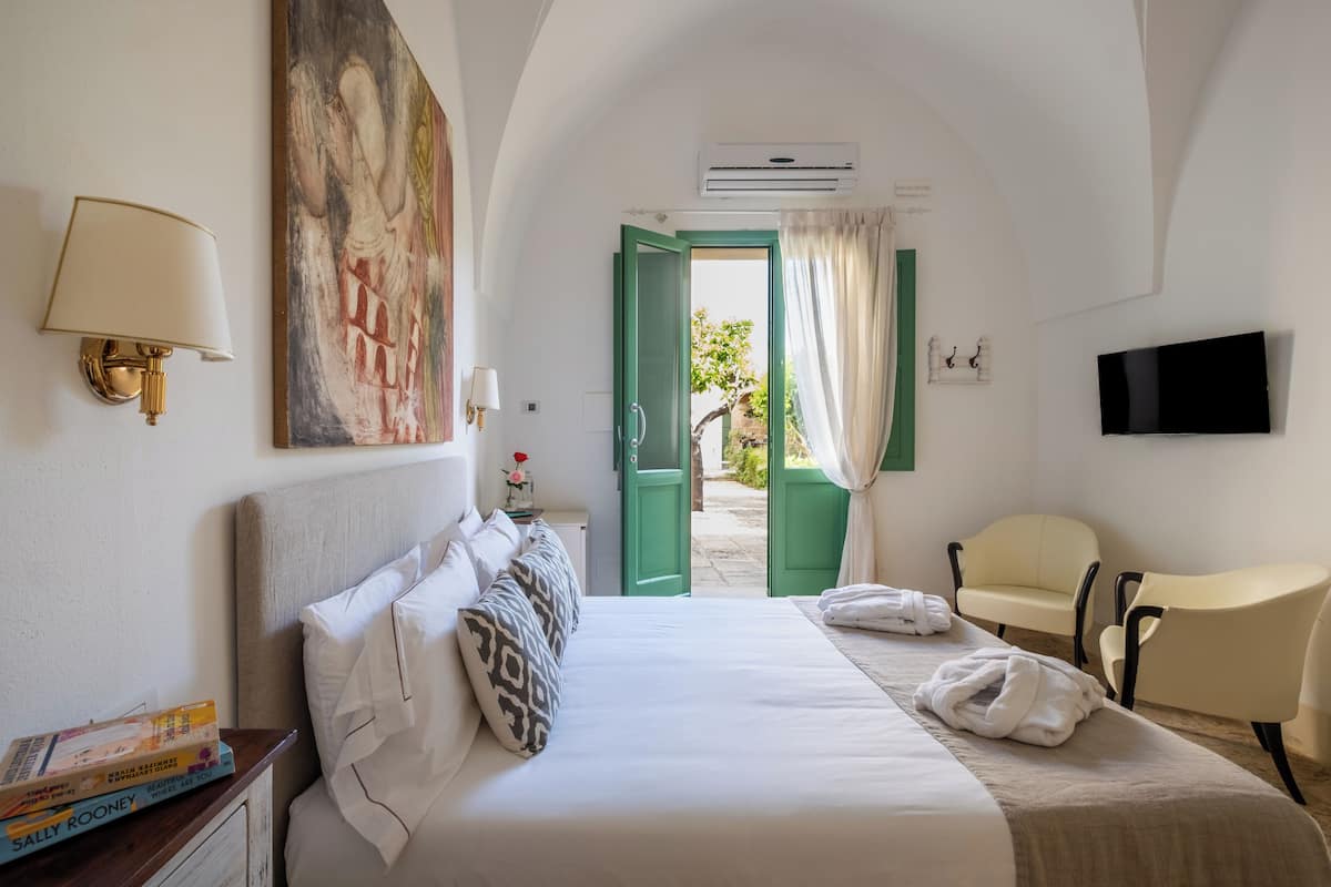 Une chambre d’hôtel avec un lit, une chaise, une télévision et un tableau au mur.
