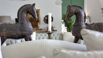 A room with a white sofa, two decorative horse statues, a white candle, and a green door in the background.