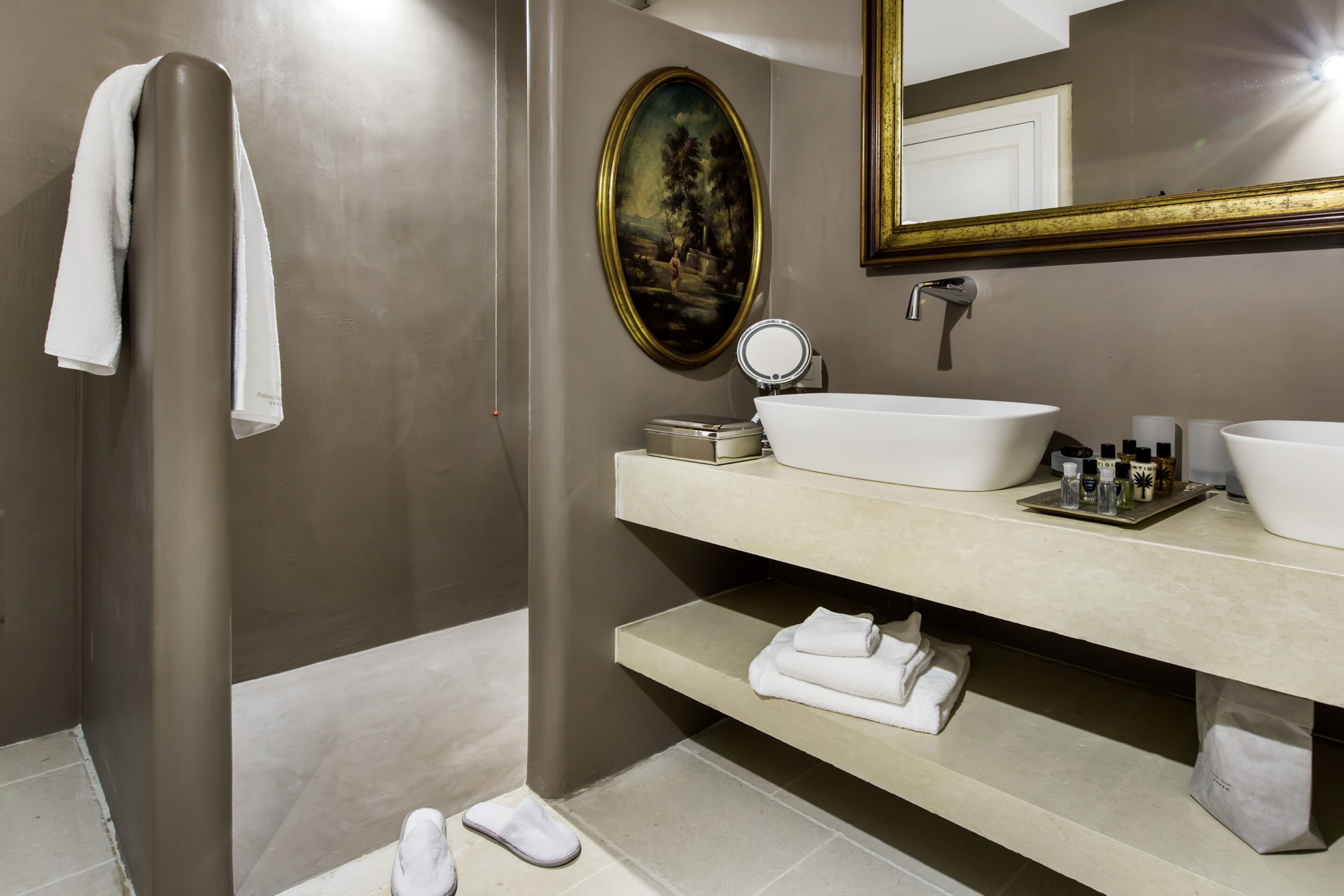 Un baño con una bañera grande, un lavabo doble, un espejo y un estante con artículos de aseo.