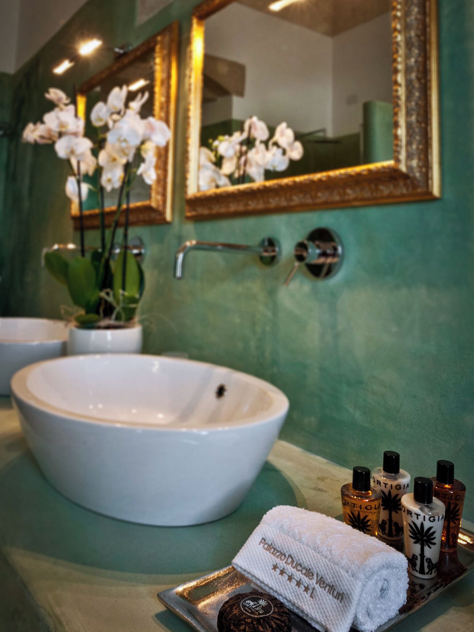Un baño con un lavabo blanco, un espejo y una bandeja con artículos de aseo.