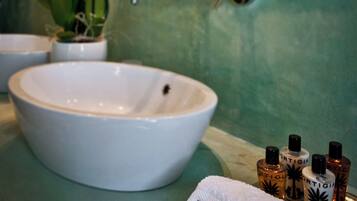 Un baño con un lavabo blanco, un espejo y una bandeja con artículos de aseo.