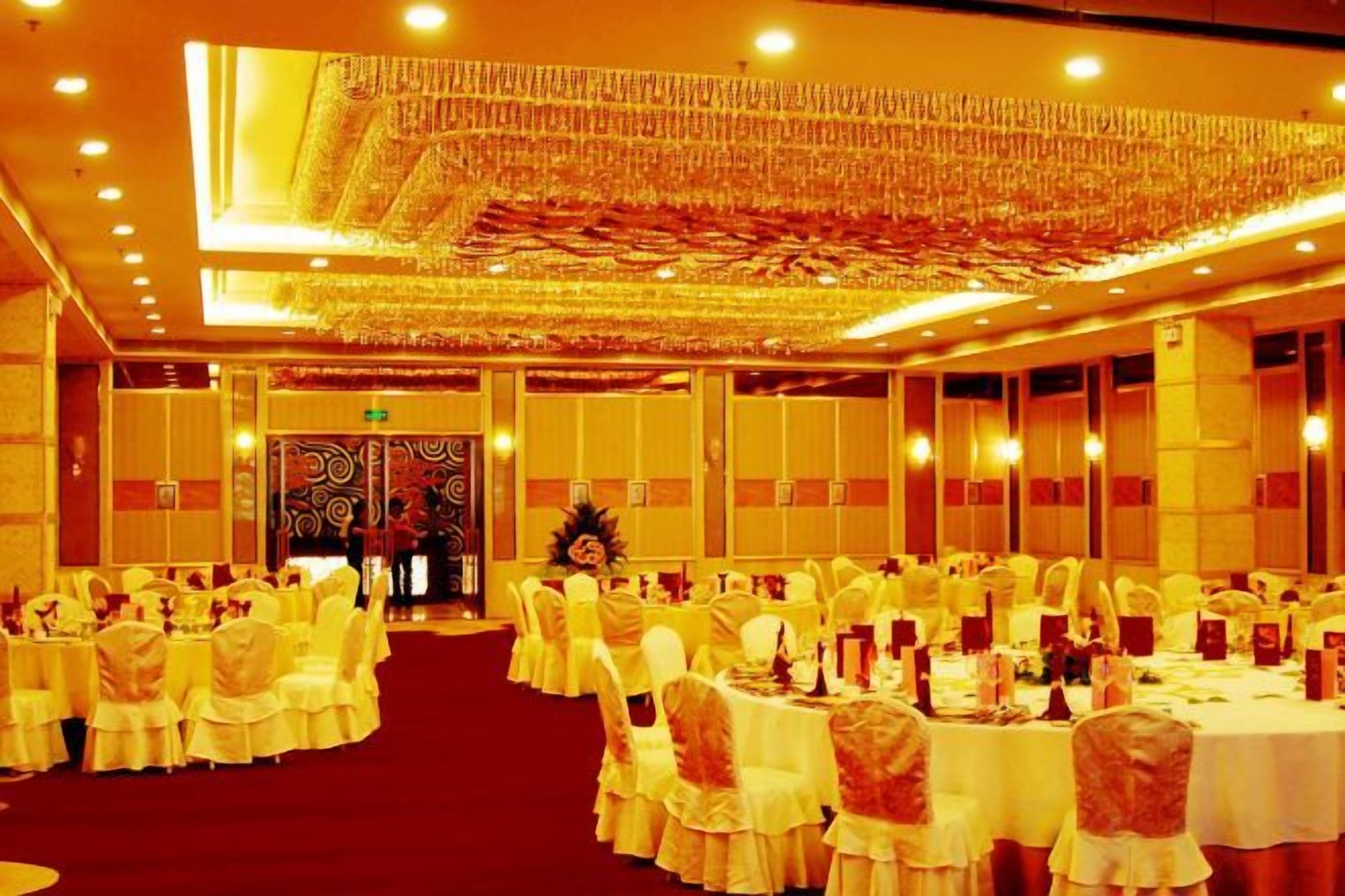 A banquet hall with round tables, white tablecloths, and chairs.