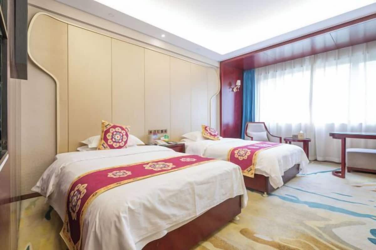 A hotel room with two beds, a desk, and a chair.