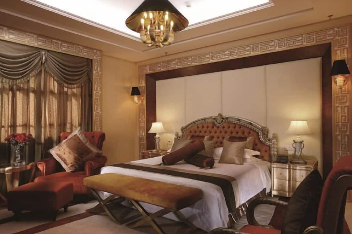 A luxurious bedroom with a large bed, ornate headboard, and a chandelier.