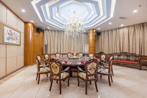 Une salle de conférence avec une table ronde, des chaises, un lustre et un canapé.