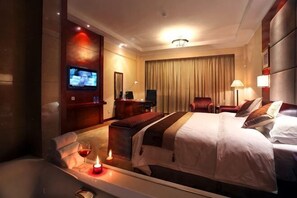 Ein Hotelzimmer mit einem großen Bett, einem Fernseher, einem Schreibtisch und einem Sessel.