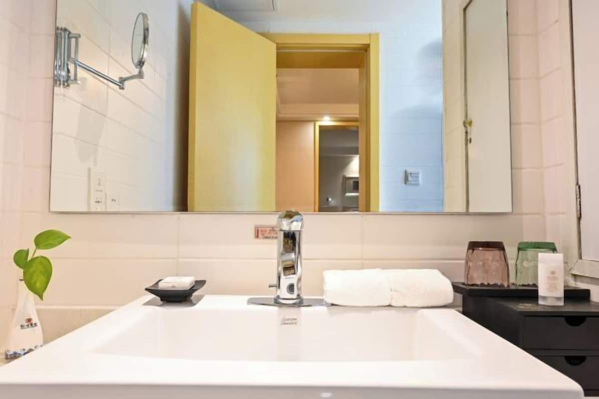 A bathroom with a large mirror, a white sink, a towel rack, and a small plant.
