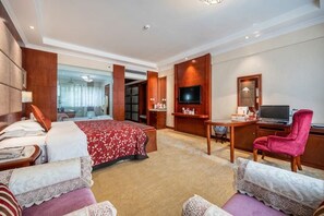 Habitación de hotel con cama, escritorio, computadora, televisor y una silla.