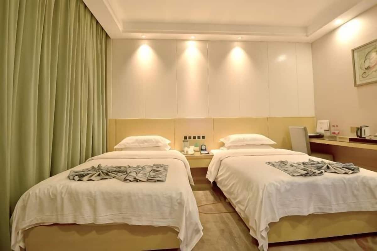 A hotel room with two beds, a desk, a chair, a nightstand, and a mirror.