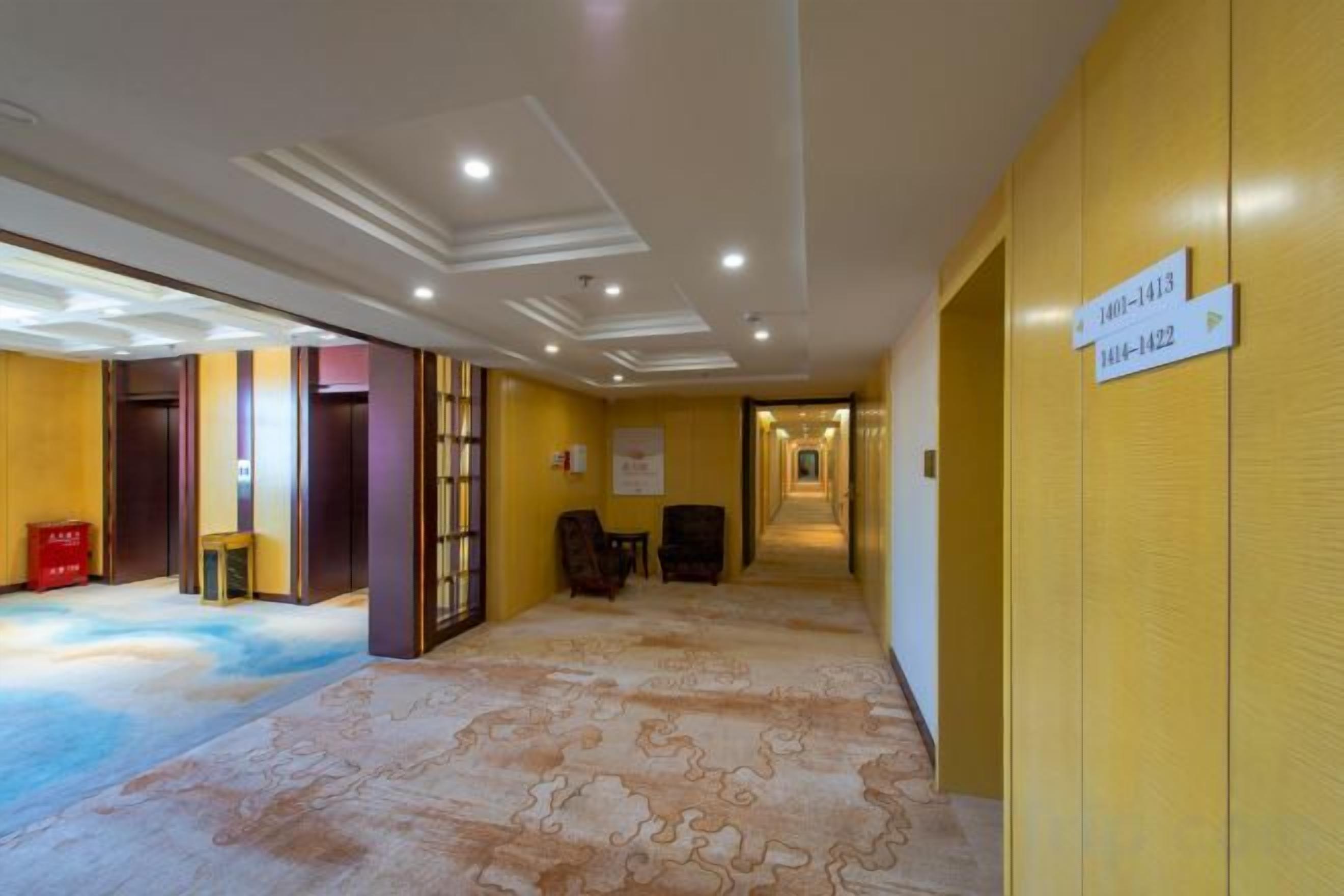 A hotel corridor with directional signs, a carpeted floor, and a door on the left.