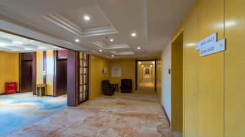 A hotel corridor with directional signs, a carpeted floor, and a door on the left.