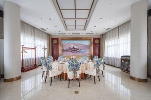 A conference room with a round table, chairs, and a large painting on the wall.