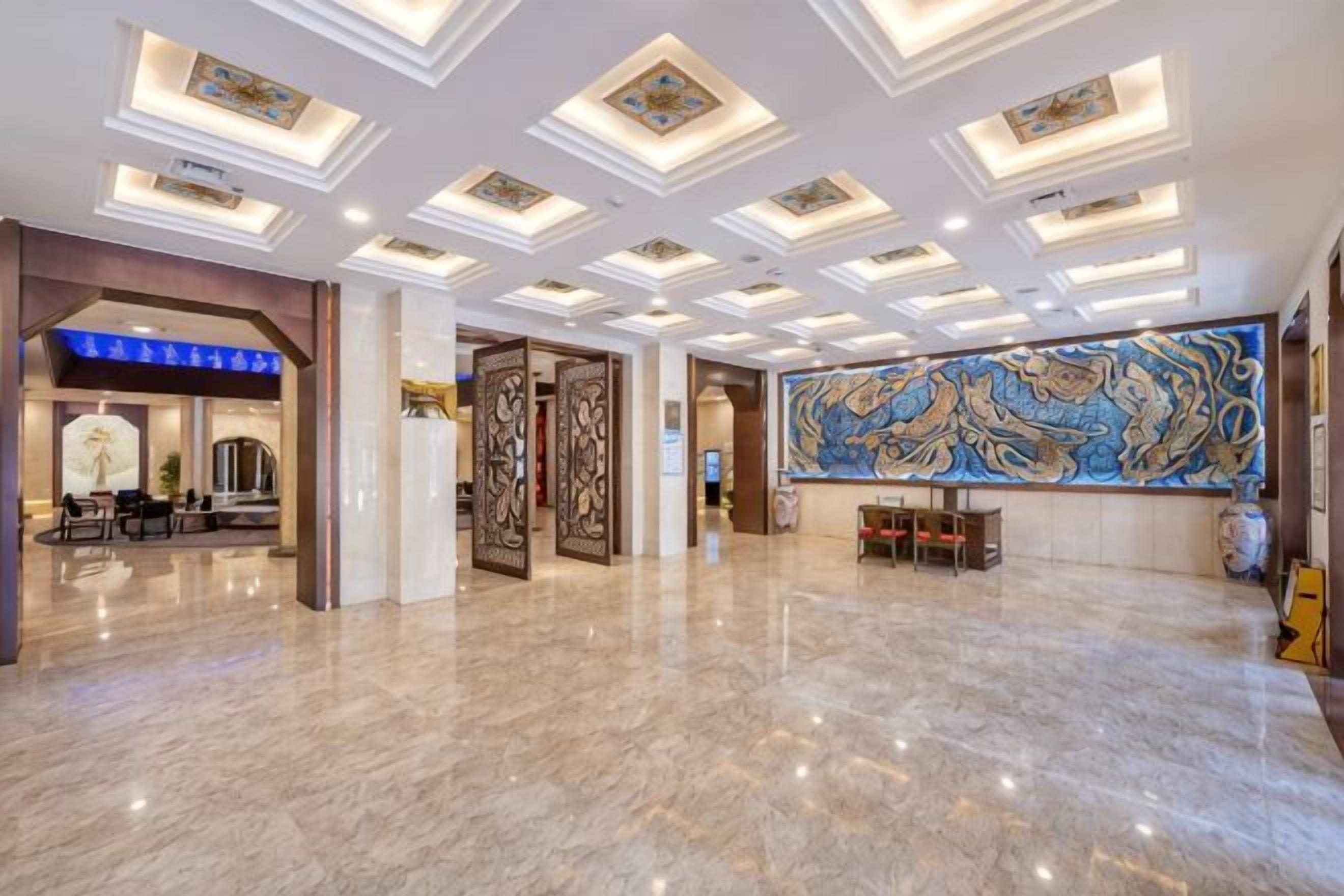 A spacious lobby with a marble floor, a reception desk, and a large decorative wall.