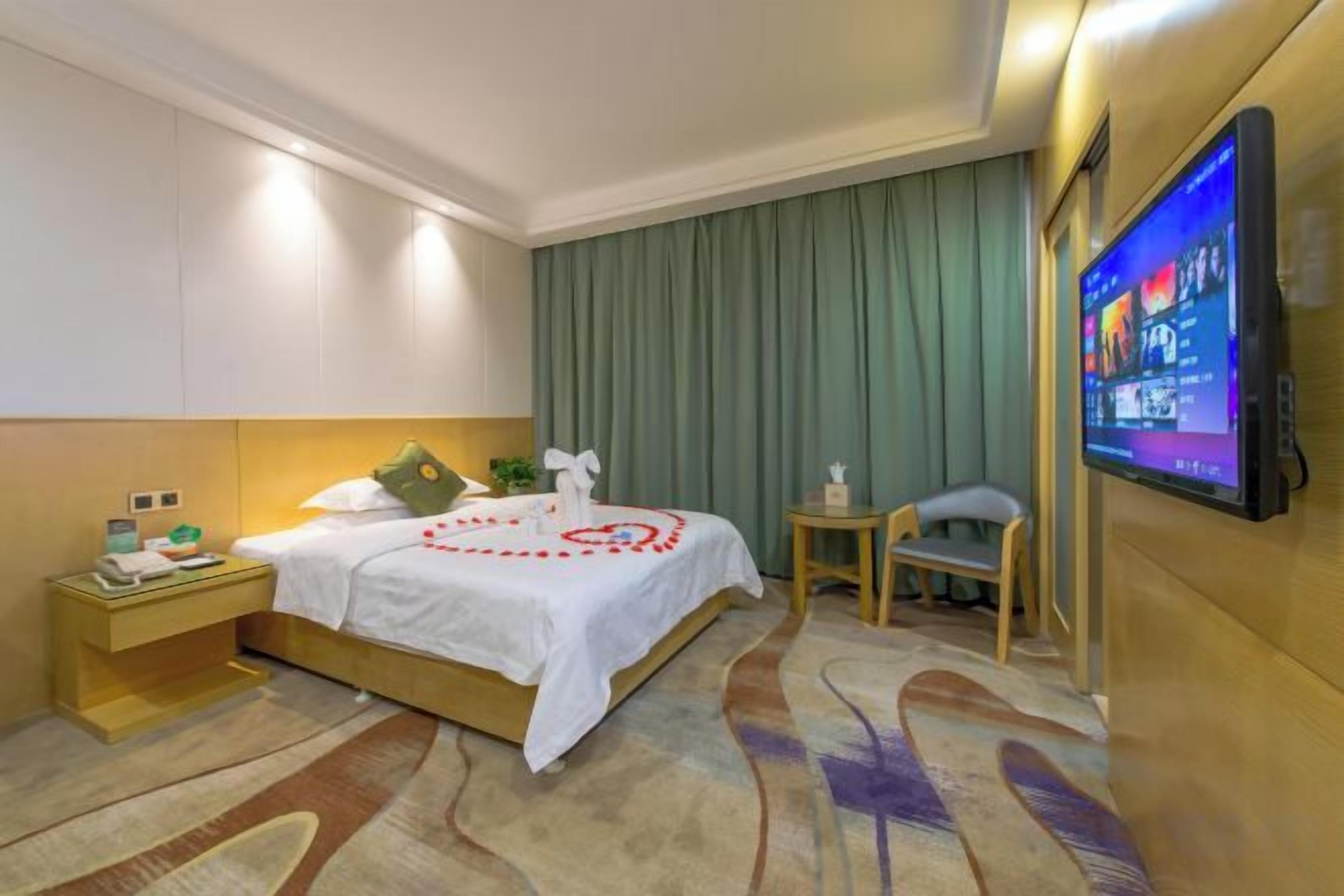 A hotel room with a bed, a television, a nightstand, and a small table.