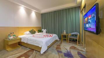 A hotel room with a bed, a television, a nightstand, and a small table.