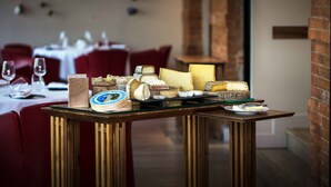 A cheese board with various types of cheese and crackers on a table in a restaurant setting. - Maison Decoret (Vichy)