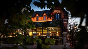 A building with a traditional architectural style, featuring a prominent entrance with a glass facade and stone pillars. - Maison Decoret (Vichy)