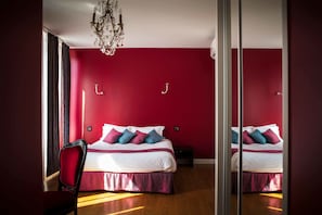 Un dormitorio con una cama grande, una araña y un espejo en la pared.
