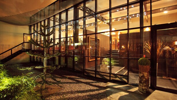A modern building with a glass facade, a staircase, and a small garden area with plants. - Maison Decoret (Vichy)