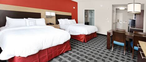 A hotel room with two beds, a desk, and a chair.