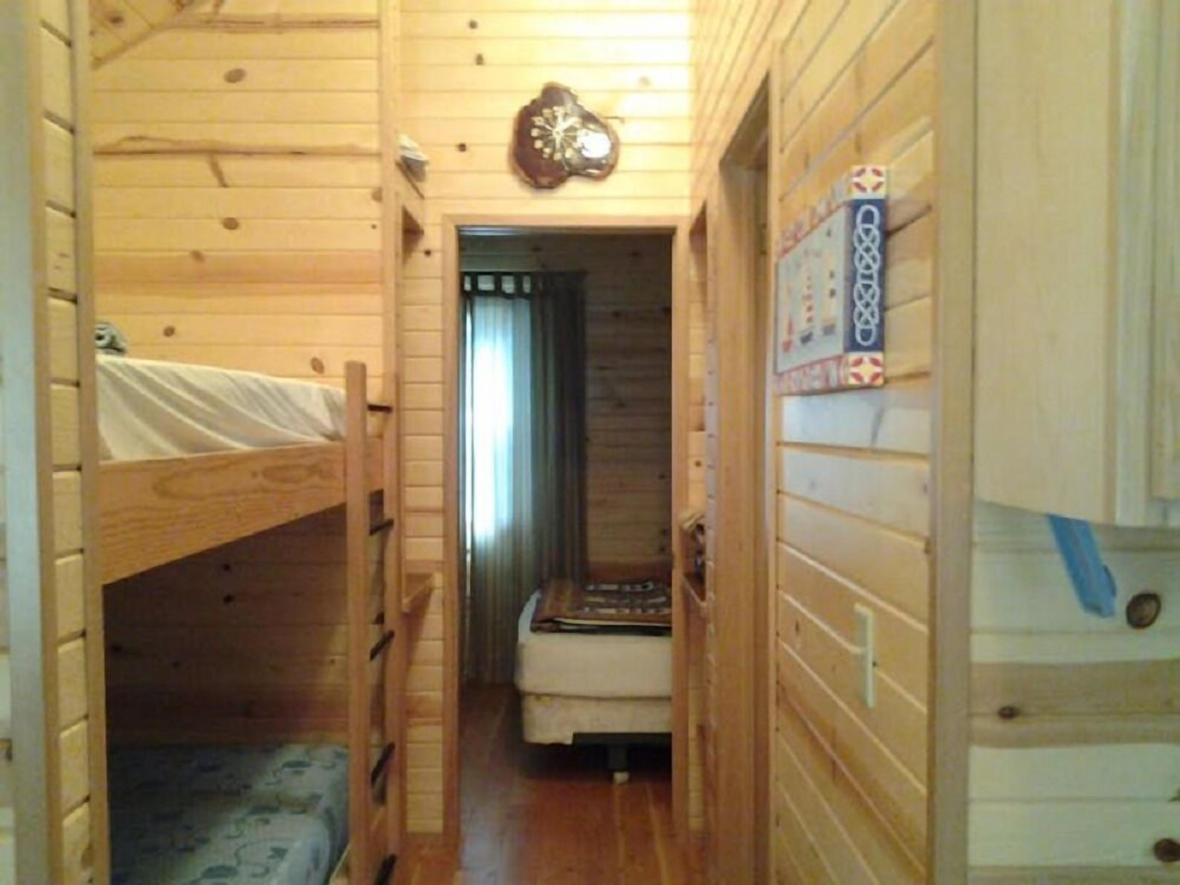 Un corridoio stretto con pareti in legno e un letto a castello a sinistra.