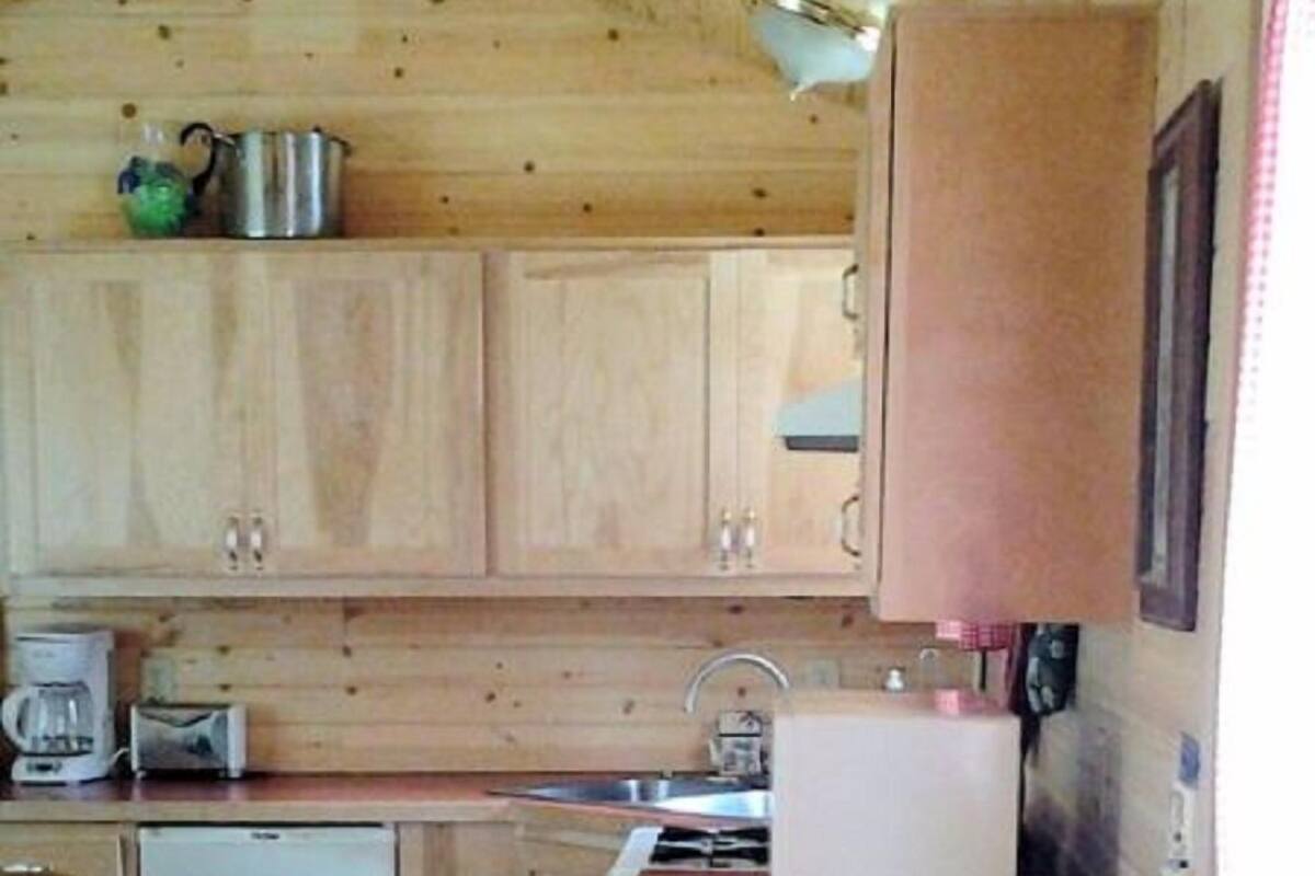 A compact kitchen with wooden cabinets, a sink, a stove, and a refrigerator.