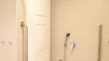 Baño con ducha, barras de apoyo y cabezal de ducha manual.