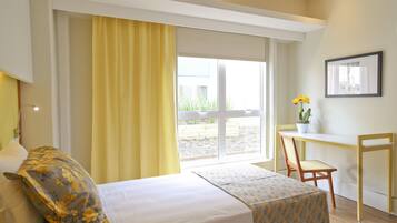 A hotel room with a bed, a desk, a chair, and a window with curtains.