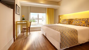 Una habitación de hotel con cama, escritorio y ventana con cortinas.