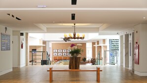 Un hall espacioso con un banco de madera central, un candelabro y una mesa de recepción.