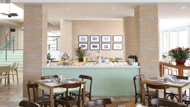 Un comedor con columnas de ladrillo, salpicadero de azulejos y cuadros en la pared.