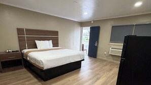 Una habitación de hotel con una cama, mesita de noche y un cubo de basura.