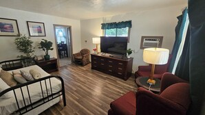 A furnished room with a bed, a sofa, a TV, a lamp, and a potted plant. - Cedar Lodge Motel (Dunsmuir)