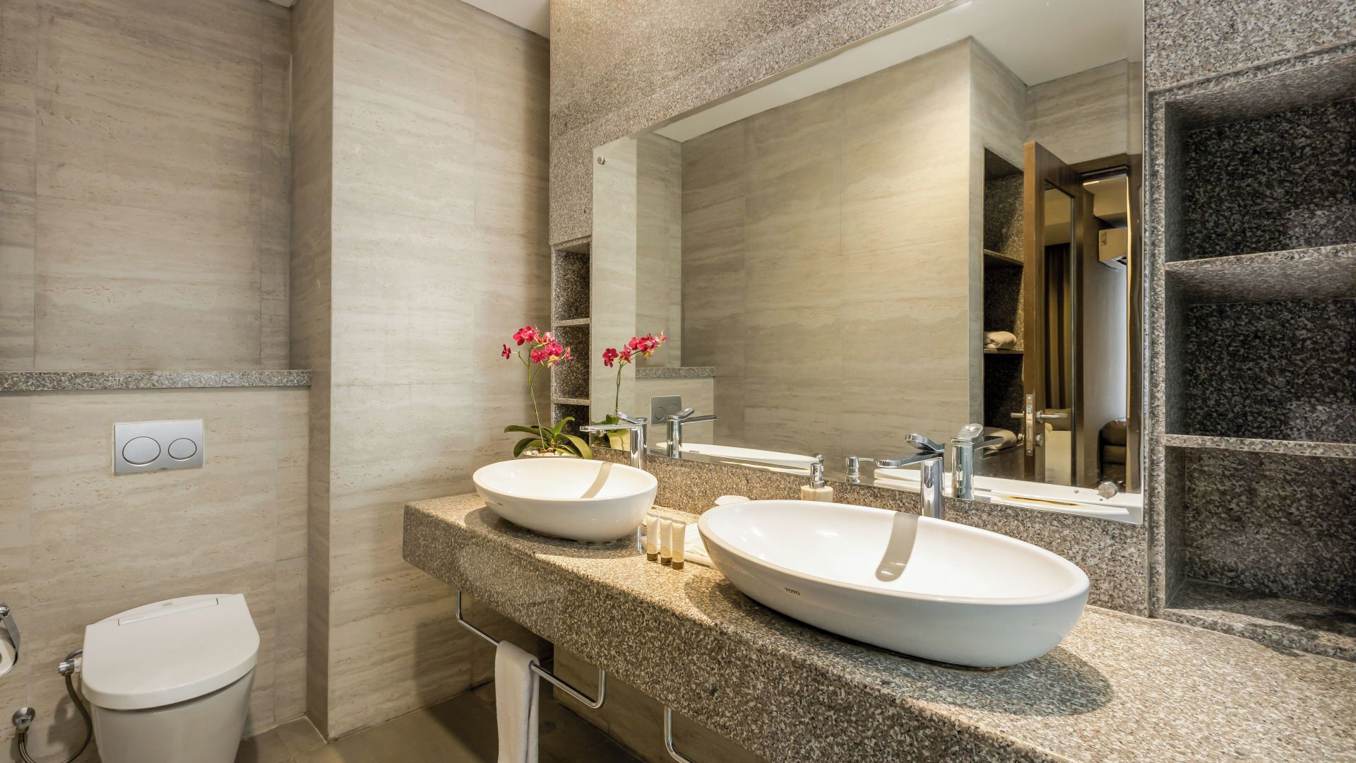 Une salle de bain moderne avec deux lavabos, des toilettes et un grand miroir.