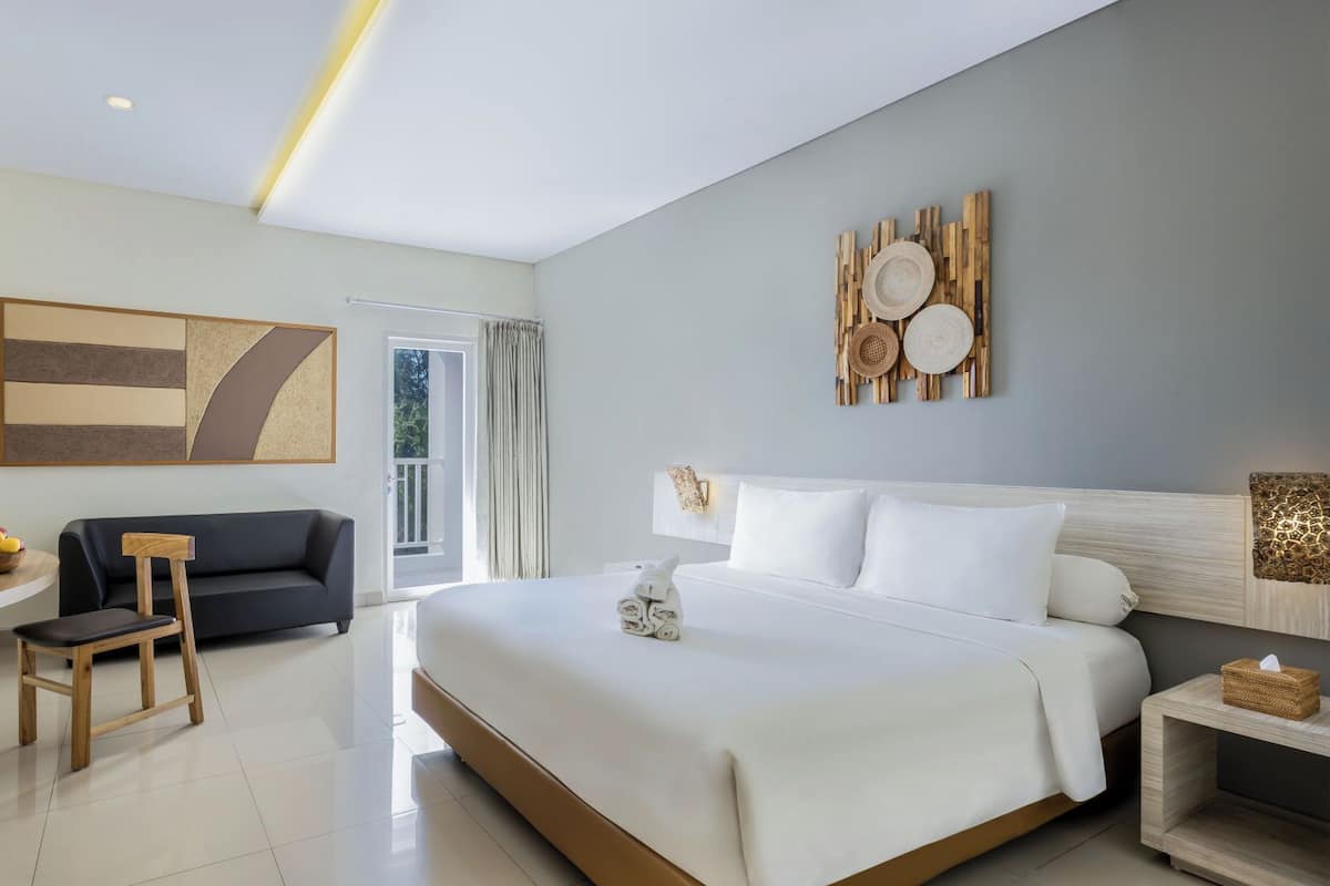 Una habitación de hotel moderna con una cama grande, un escritorio, un sofá y un televisor.