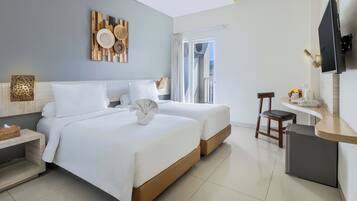 Habitación de hotel con dos camas, un escritorio, una silla, un televisor y una ventana con cortinas.