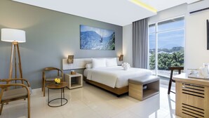Una camera d'hotel moderna con un letto grande, una scrivania, una sedia, un comodino e vista sull'esterno.