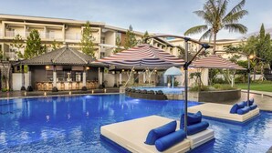 Una piscina con lettini e ombrelloni, una zona bar e un elemento d'acqua.
