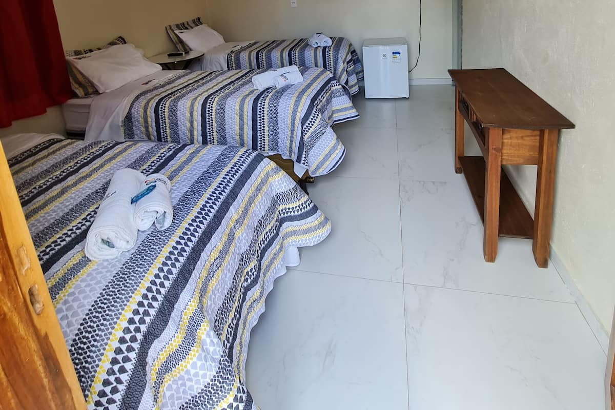 Een hotelkamer met twee bedden, een houten tafel en een aan de muur bevestigde televisie.