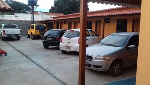 Un espace de stationnement où sont garées plusieurs voitures, dont un pick-up blanc, un VUS jaune et une berline argentée.