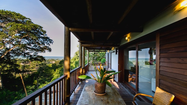 A wooden deck with a table and chairs, a potted plant, and a view of the landscape. - Morena Casa & Hotel (Trancoso)