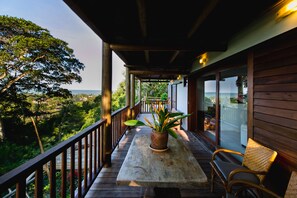 A wooden deck with a table and chairs, a potted plant, and a view of the landscape. - Morena Casa & Hotel (Trancoso)