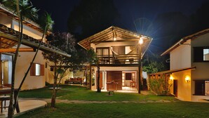 A two-story house with a balcony, a dining area, and a small garden. - Morena Casa & Hotel (Trancoso)