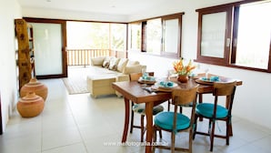 A dining area with a wooden table and chairs, a sofa, and a view of the outdoors. - Morena Casa & Hotel (Trancoso)