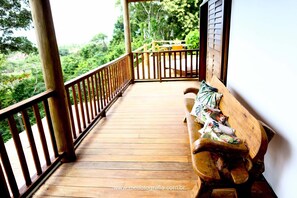 A wooden deck with a wooden bench and a railing.